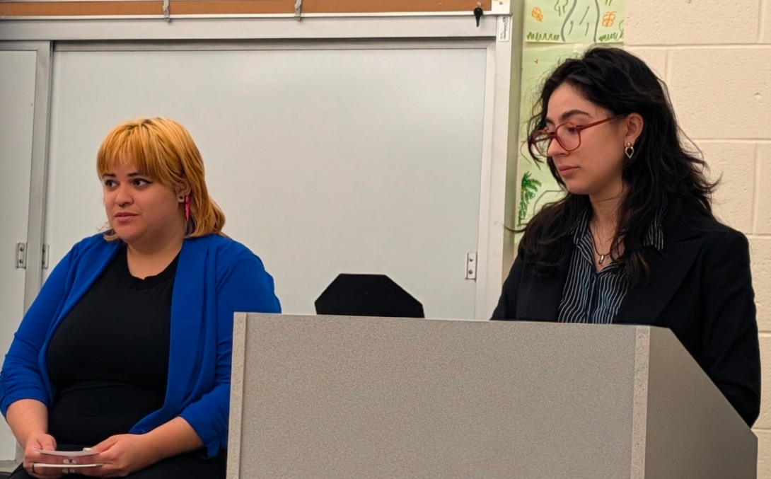 Two students at a podium presenting research.