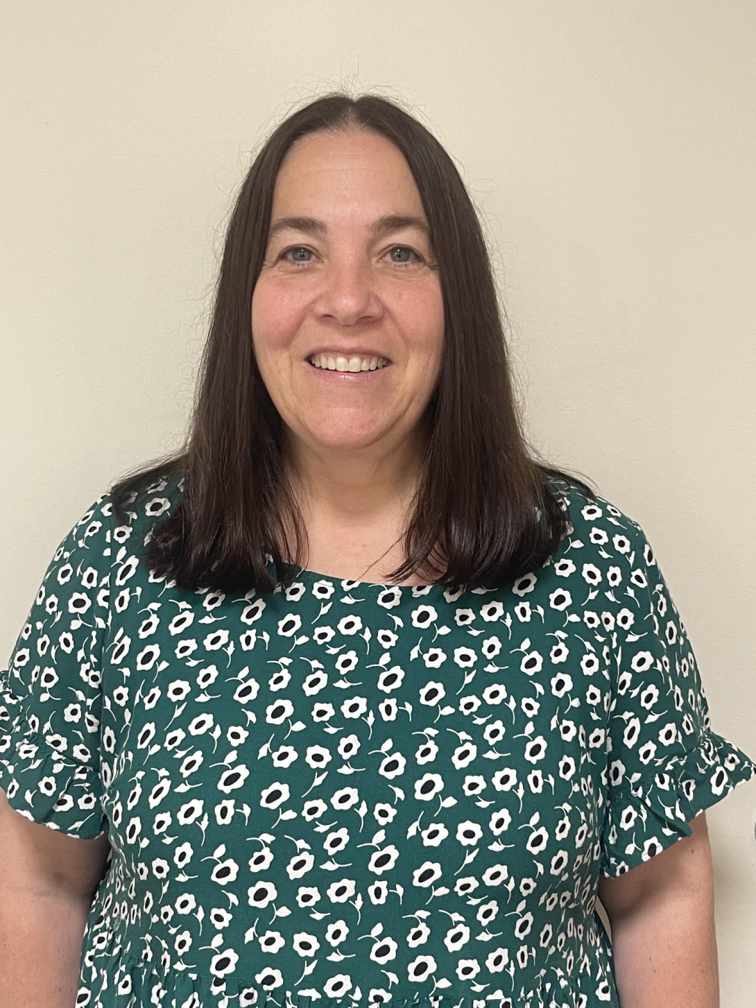 Director of Student Disability Services smiling in front of a white wall.