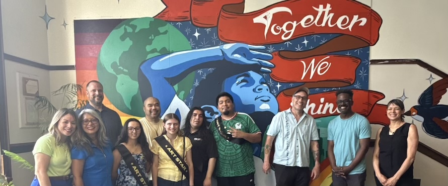 A photo of Northeastern Illinois University students and employees with employees from Hyat Elementary and 46th Ward Alderwoman Leni Manaa-Hoppenworth standing in front of the new mural, "Together We Shine," at Hyat Elementary.  