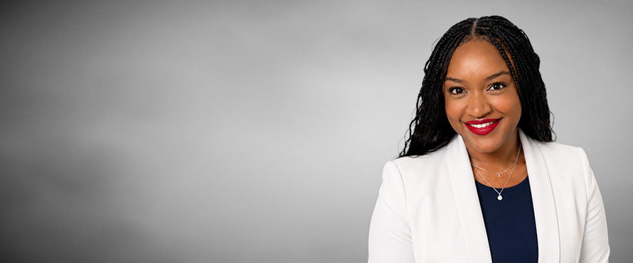 A headshot photo of Kiantra D. Loza, Ed.D., smiling, wearing a white blazer and dark blouse, against a gray background.