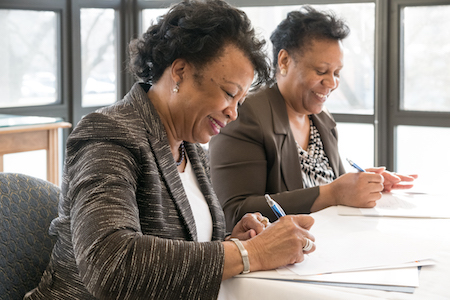 Northeastern President Gloria J. Gibson (left) and Black Ensemble Theater Founder and CEO Jackie Taylor smile as they sign agreements.