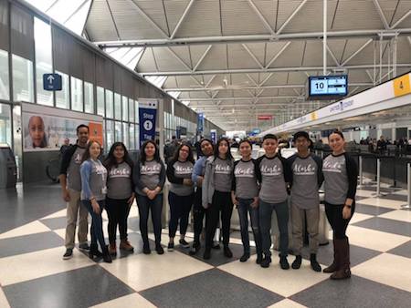 A group of students poses in an airport terminal.