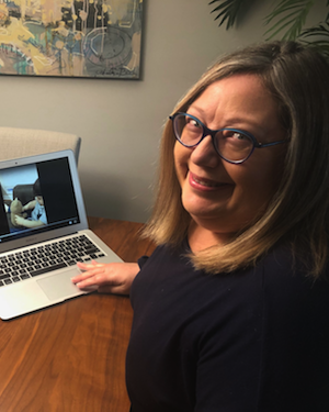 Elizabeth smiles into the camera with her computer in the background.