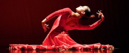 A dancer wearing a red dress against a black background
