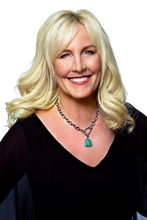 Erin Brockovich smiles into the camera in front of a white background.