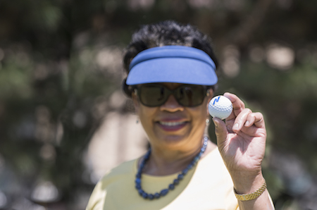 President Gibson holds up a golf ball and smiles at the camera