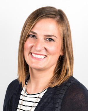 Jessica Aulisio smiles into the camera in front of a white background.