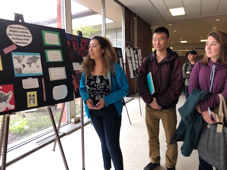 Students look at a Justice Studies poster display in Village Square 