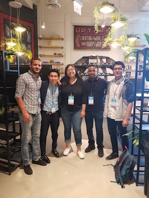 Five Northeastern students pose for the camera in an office lobby.