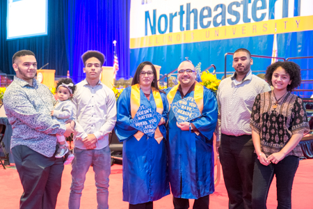 Ruby and Joel Rodriguez pose with their family in front of the Commencement stage.