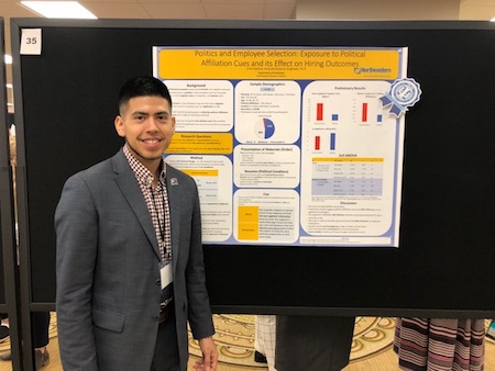 Uriel Saldivar smiles in front of his winning poster presentation.