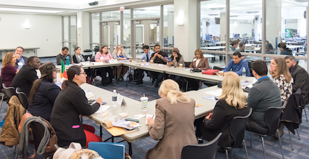 Fourteen foreign visitors to Northeastern sit at a large table