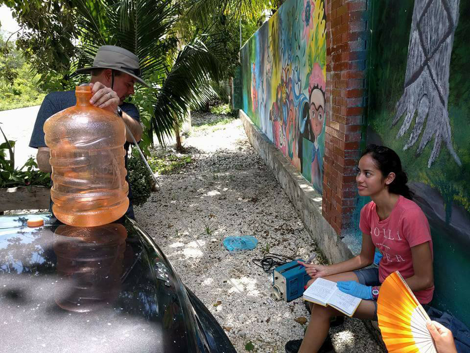 "Ken talking to a student in the street near a colorful mural"